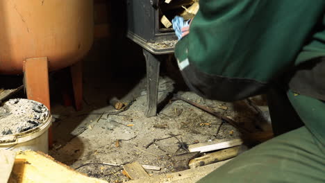 poner leña y papel en una chimenea de metal para calentar el taller