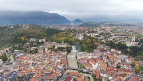 Vista-Pintoresca-Del-Centro-De-Lazio,-Cascada-Isola-Del-Liri,-Palacio-Fortificado-Y-Montañas-En-El-Fondo-En-Un-Día-Nublado,-Italia,-Antena