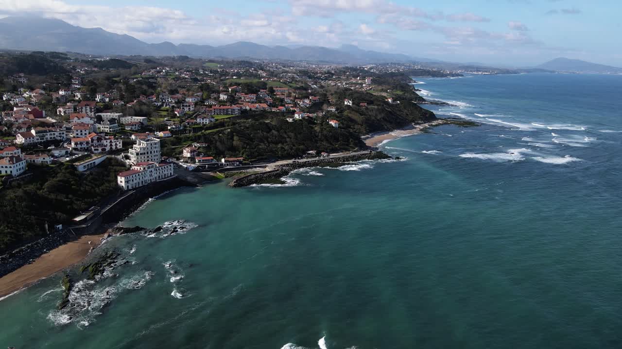 vista aérea de la costa francesa del país vasco con cientos de casas de estilo vasco y olas rompiendo en la playa y arrecifes debajo