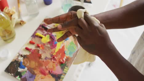 Mid-section-of-african-american-male-artist-cleaning-his-hands-at-art-studio