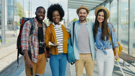 grupo multiétnico de amigos viajeros sonriendo y mirando la cámara en la estación de tren