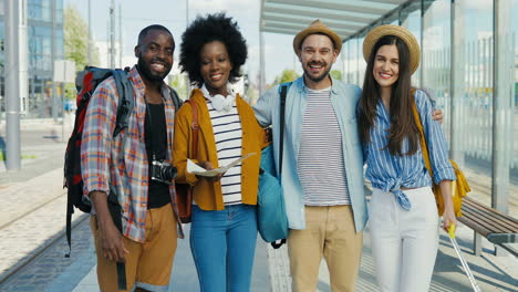 multiethnic group of friends travellers smiling and looking at the camera at train station