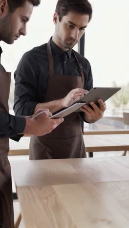 a man wearing an apron is looking at a tablet