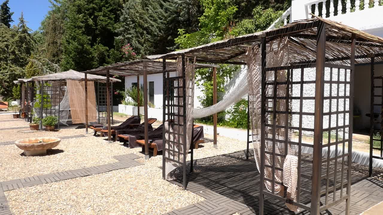 General view of a row of wooden and reed gazebos with sun loungers, designed for relaxation and rest. Located in the outdoor area of a spa