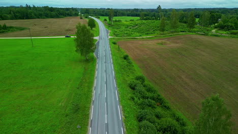 Vista-Aérea-De-Una-Carretera-De-Dos-Carriles-En-Un-Paisaje-Rural-Con-Tierras-Agrícolas