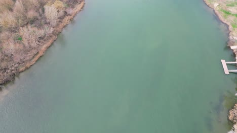 Miravet-town-in-tarragona,-spain,-showing-a-serene-river-with-autumn-foliage,-aerial-view