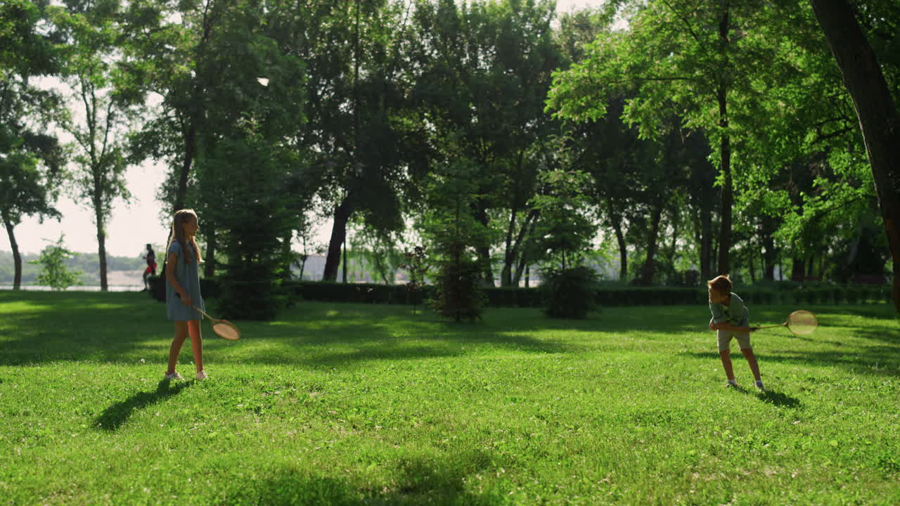 два радостных брата и сестры играют в бадминтон в солнечный летний день. семейный пикник в выходные.