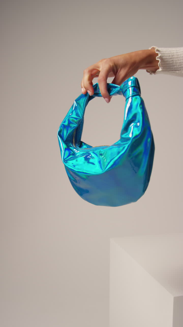 여성 소셜 미디어 인플루언서가 다양한 색의 패션 드백을 들고 사용자 생성 콘텐츠를 생산하는 점프 으로 편집된 클로즈업 수직 비디오