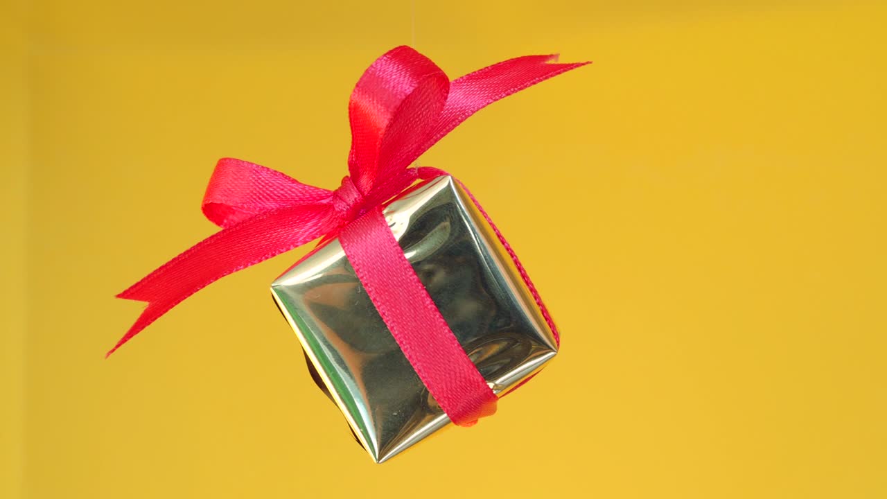caja de regalos con cinta roja girando sobre fondo amarillo. rotación de 360 grados