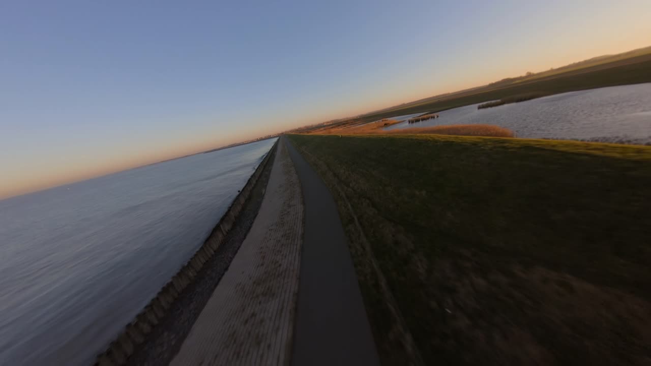 Fast shot revealing the sea behind the dykes during sunset