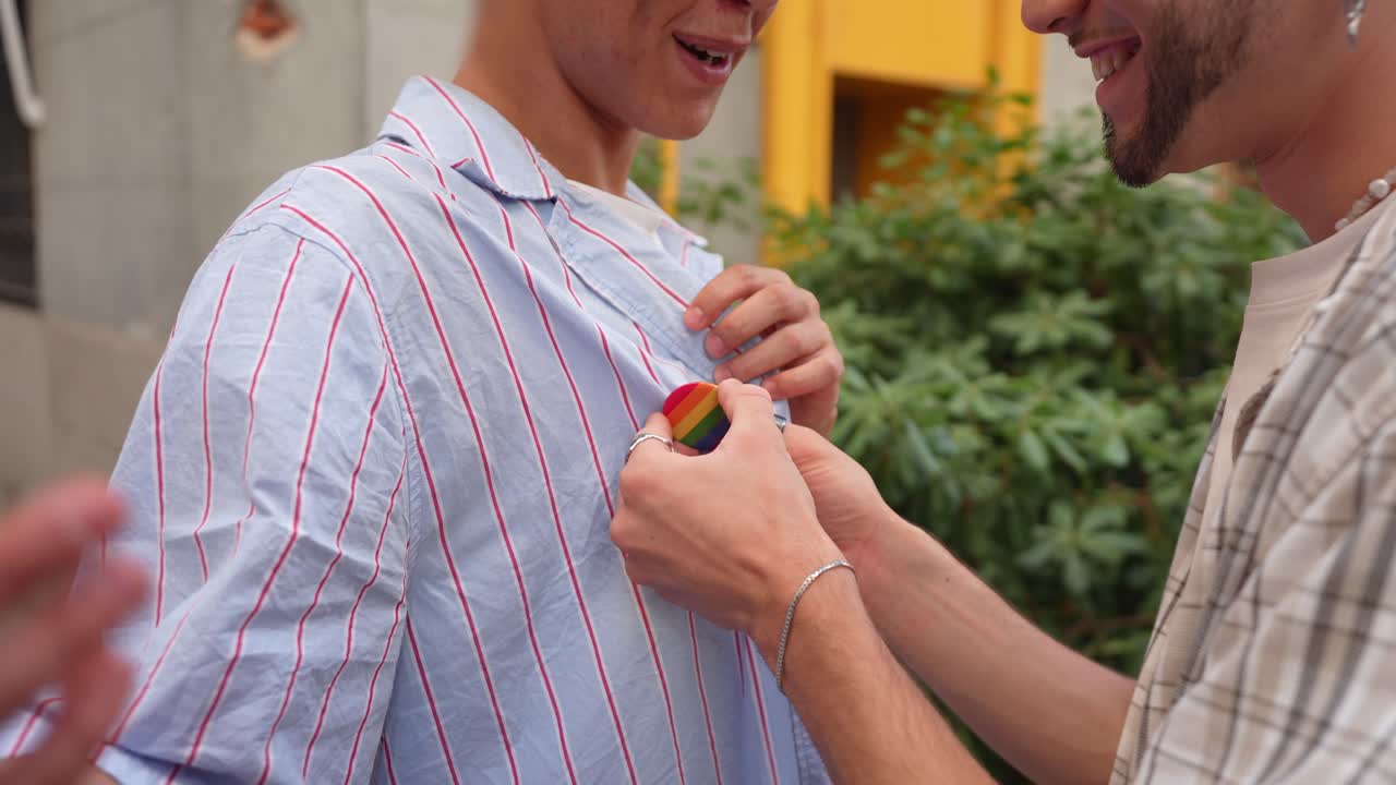 Young Man Attaching Rainbow Pride Pin to Partner's Shirt