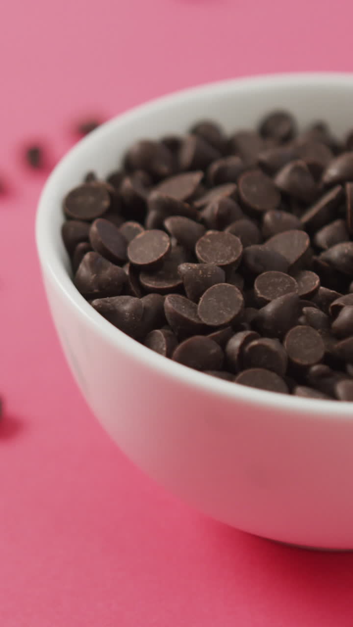 video de un cuenco de trozos de chocolate sobre un fondo rosado
