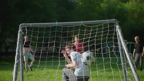 a goalkeeper watches in dismay as the ball is shot into the net, narrowly crossing over his head. he covers his face in shame as the ball scores, while other players react in the background