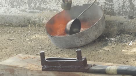 plomo fundido que se vierte en una cuchara de metal en un taller, entorno polvoriento, de cerca