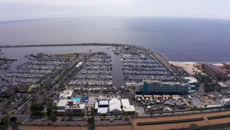 Aerial-high-and-wide-panning-shot-of-the-King-Harbor-Marina-looking-out-to-the-Pacific-Ocean-in-Redondo-Beach,-California