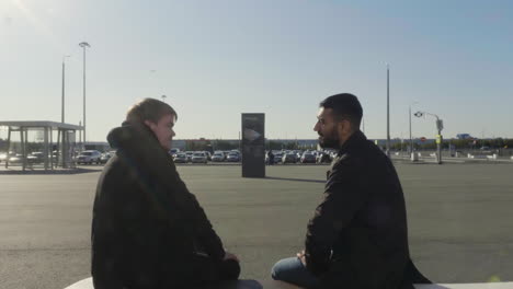 two men talking at airport parking lot