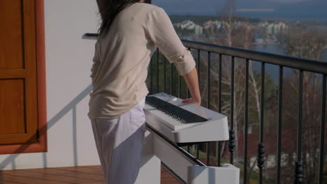 woman playing piano on balcony with scenic view