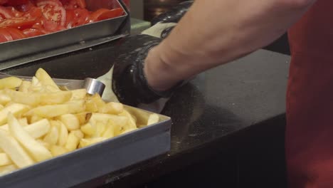 chef preparing a delicious wrap with french fries and tomatoes