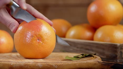 la mano masculina con un cuchillo cortó el pomelo en pedazos.