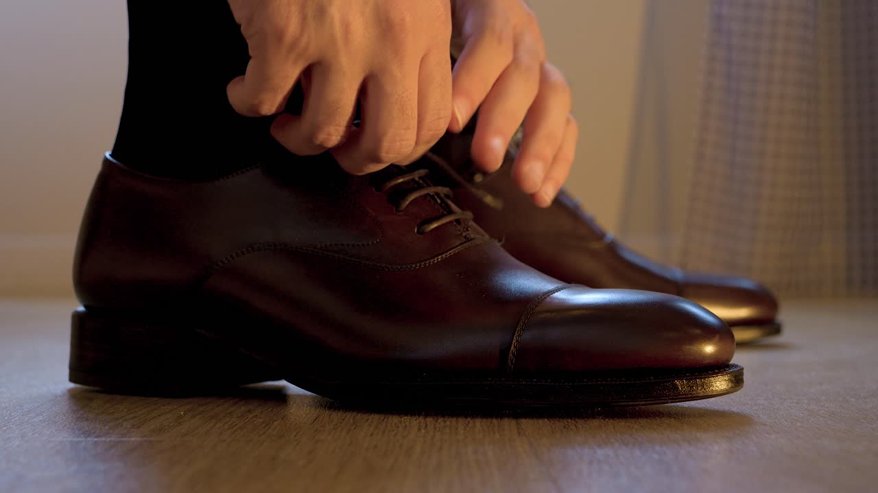 Close-up of a man tying his black leather wedding shoes