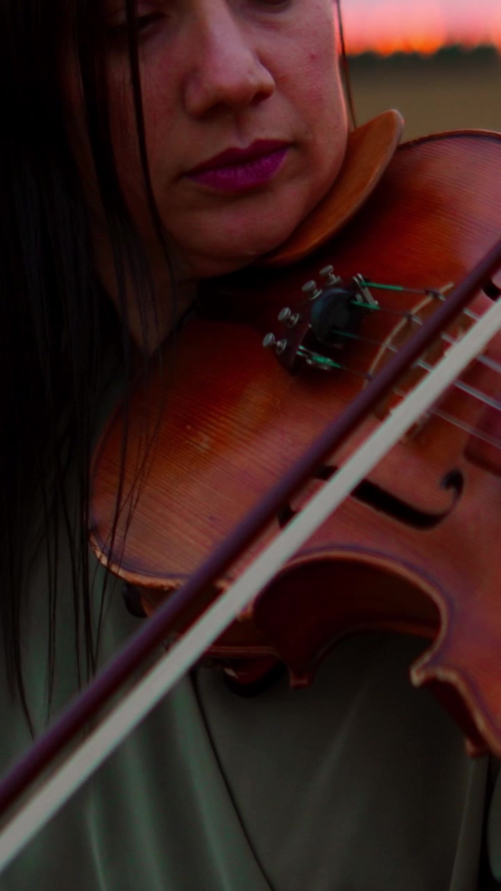 Woman Playing Violin Outdoors at Sunset