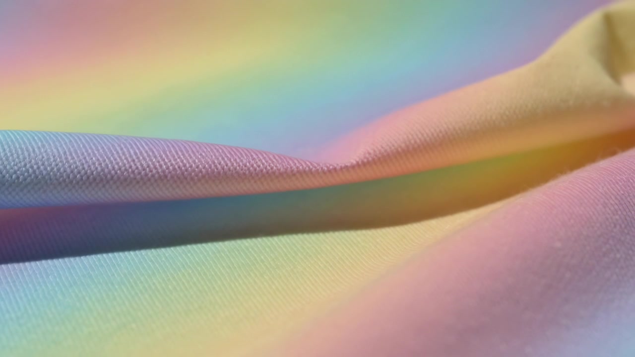 Shifting colored lights producing shimmer across woven fabric on tabletop, highlighting weave