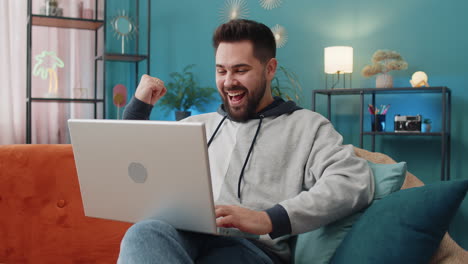 amazed young man use laptop computer receive good news message shocked by victory celebrate win