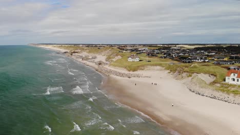 aerial of the beautiful danish west coast with white sand beaches and beautiful waves and and old house in front of some old german bunkers