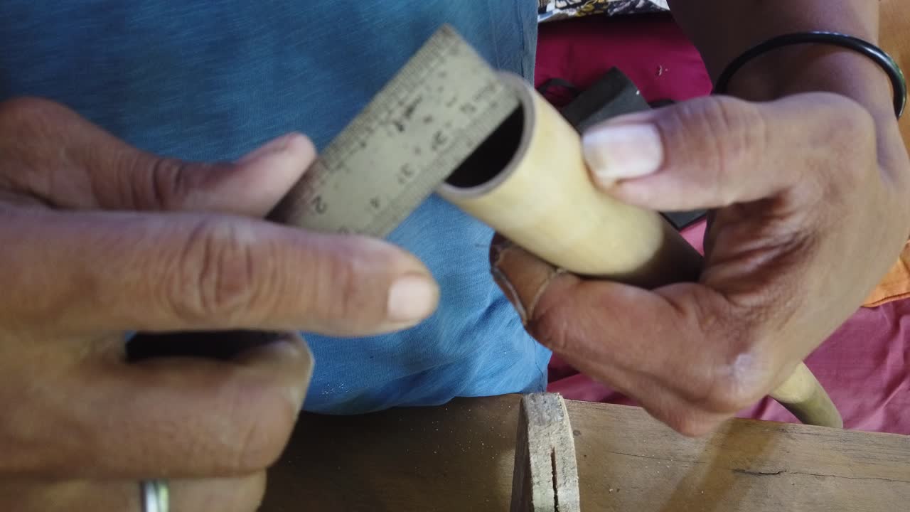 Close up shot of artisan hands polishing a hand made bamboo flute in a workshop