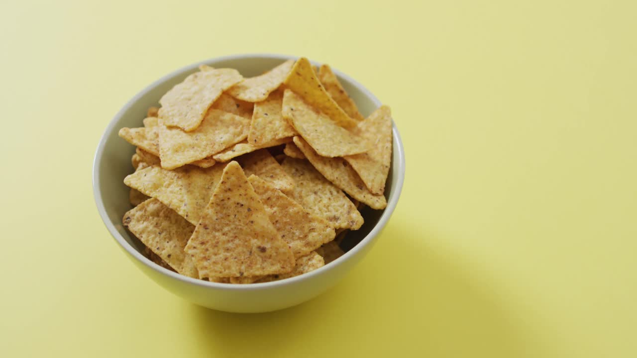 acercamiento de nachos en un tazón con espacio de copia en la superficie amarilla