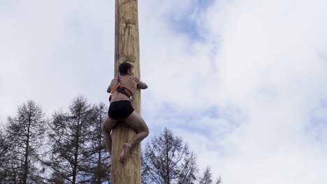 person climbing a tall wooden pole