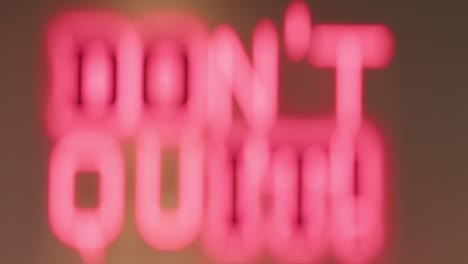an athlete standing infront of a sign written on it don't quit then leave frame while wearing headphones, close up shot