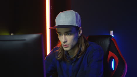 close up view of young man wearing cap and playing a game on the computer and annoyed by losing 1