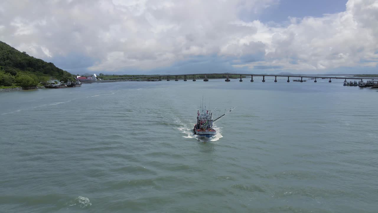 barco de pescadores saliendo del muelle con vistas a la montaña en tailandia