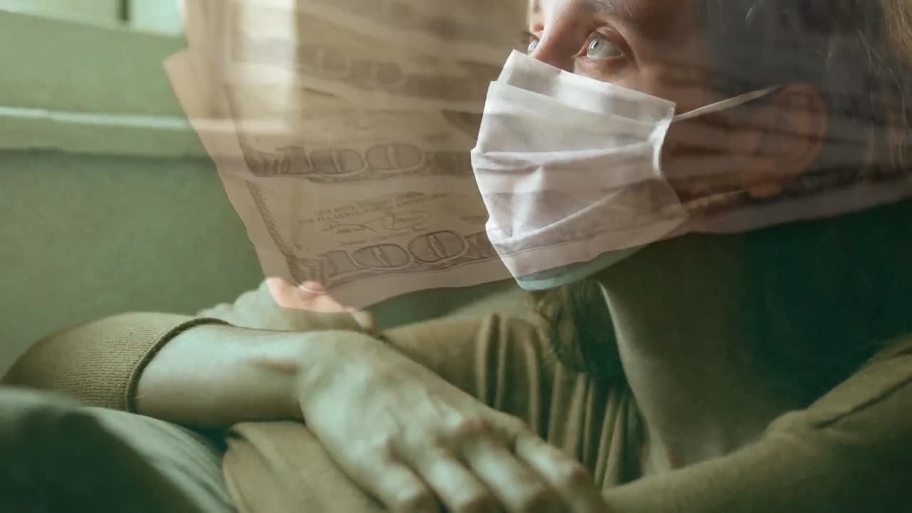 백그라운드에서 얼굴 마스크를 쓰고 있는 여성을 상대로 움직이는 미국 달러 지폐의 디지털 복합 비디오