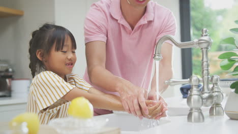 asian father helping daughter to wash hands with soap at home to stop infection in health pandemic