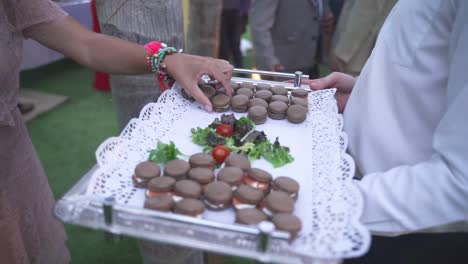 guest picking up a dessert from a tray during a formal outdoors event