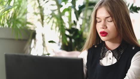 mujer joven trabajando en una computadora portátil en un café