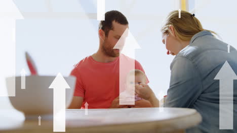 Animation-of-white-arrows-over-caucasian-couple-with-baby-by-table