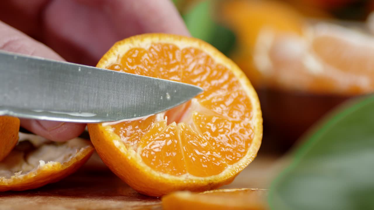la mano de un hombre con un cuchillo exprime el jugo de mandarina.