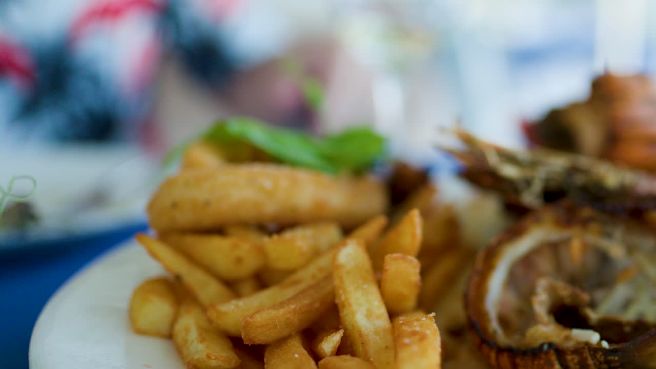 Primo piano di un piatto di frutti di mare con patatine fritte, crostacei grigliati, guarnizione di limone, luce naturale, messa a fuoco superficiale