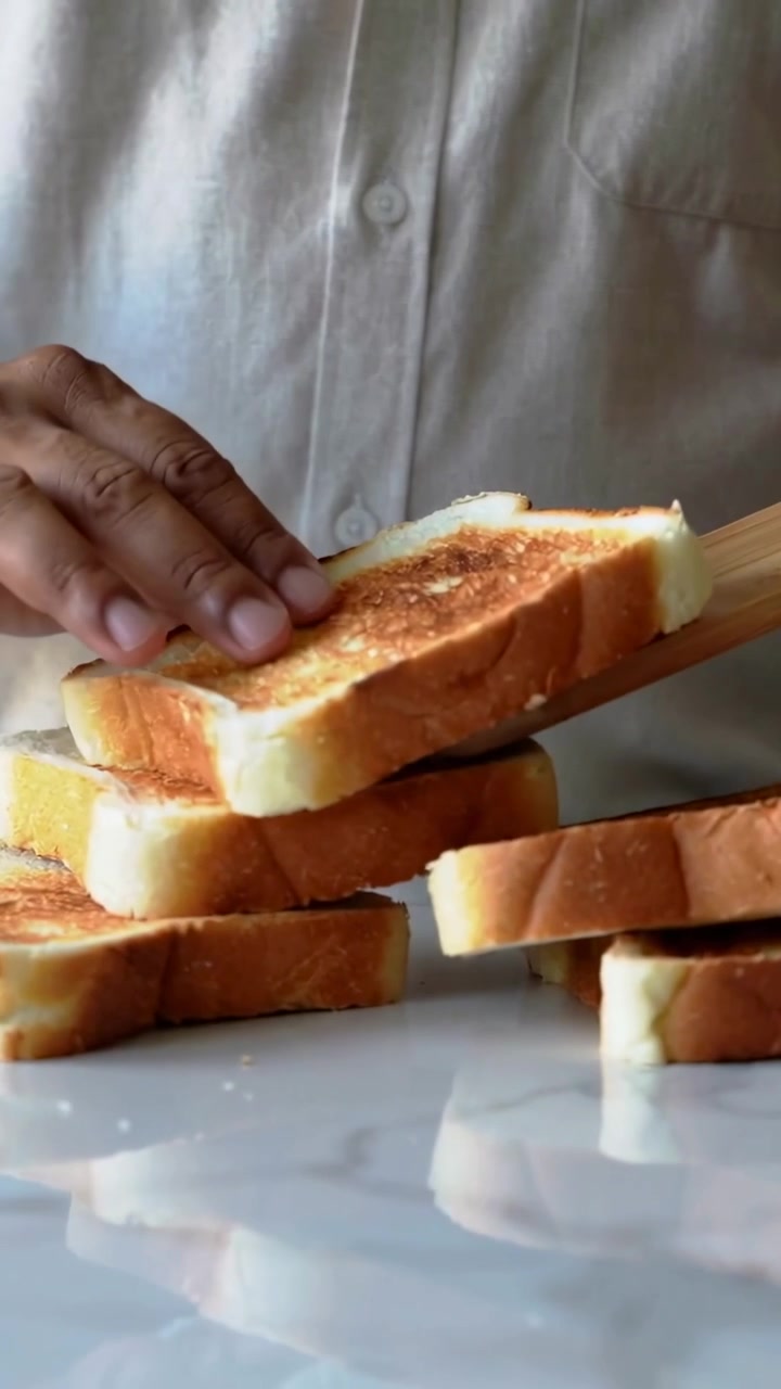 Vertical video: Lowering paddle, shirted hands stacking toast on kitchen counter, stabilizing stack