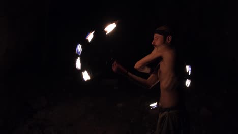 a young male performer dances with a fire fan