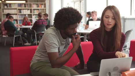 female university student working in library with tutor