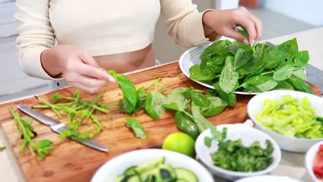 hands preparing fresh basil on a wooden board in a bright kitchen. natural lighting enhances the vibrant green colors