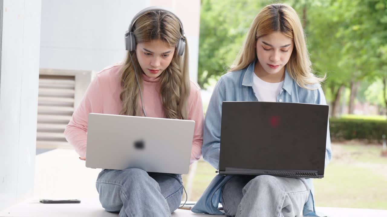 Two Asian girls student partners are working on a laptop help study together