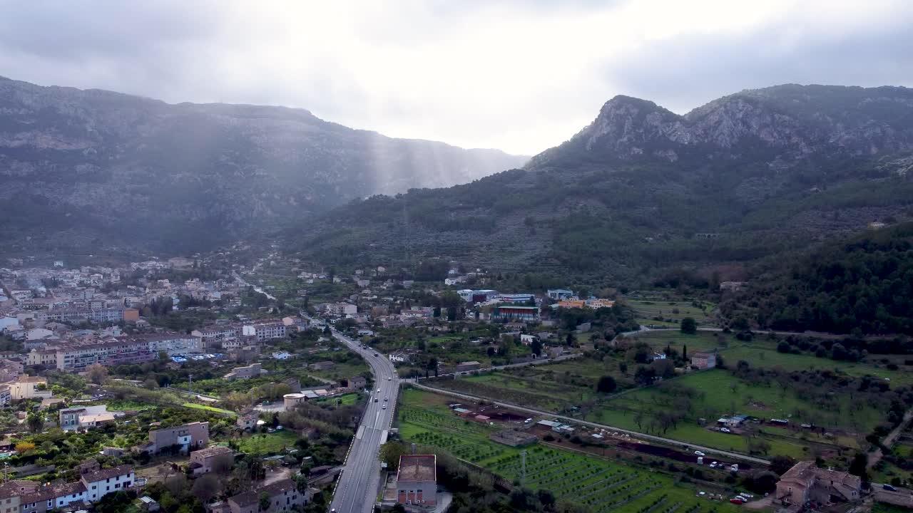 Sole che filtra tra le nuvole su un villaggio di montagna a Soller, Maiorca