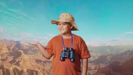 asian boy with a hat and binoculars smiling and pointing to side while traveling at the top of mountain. boy researcher examines something, travel tourism adventure, close up