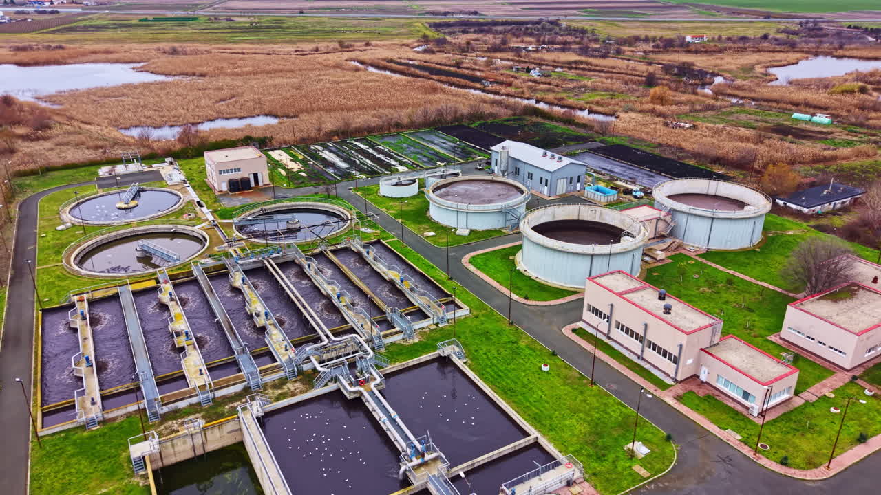 Water treatment facility processes wastewater in rural area with large tanks and diverse landscape present