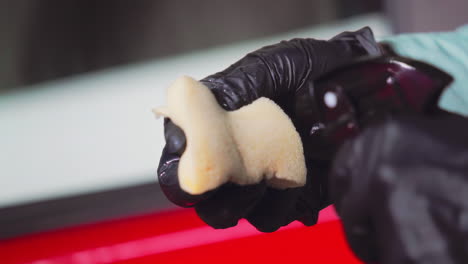 hand with black gloves spraying foam into sponge scrub